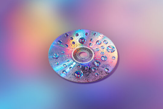 CD disc with water drops on mirrored surface on holographic back - Powered by Adobe