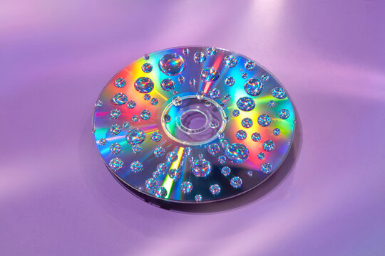 Compact CD disc splattered with water refracting rainbow light