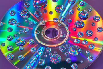 Close up of compact disc with iridescent light and water drops