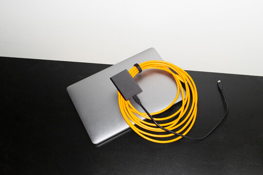 Silver laptop and orange wire with hard direct flashlight