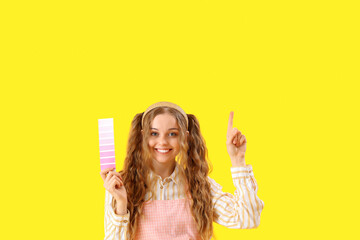 Female artist with paint color palette pointing at something on yellow background