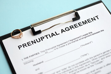 Prenuptial agreement and wedding ring on table. Premarital paperwork process close up