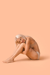 Body positive mature woman sitting on beige background