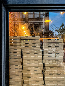 Pizza boxes stacked in window
