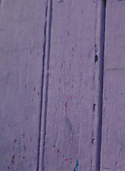 Old textured surface painted with purple peeling paint.