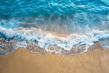 High-angle shot of a wave cresting and gently lapping onto a sunny golden beach, evoking calmness...