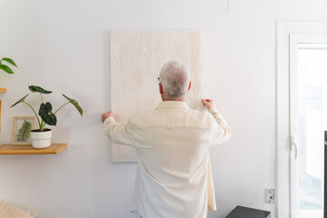 Man Hanging Painting On Wall