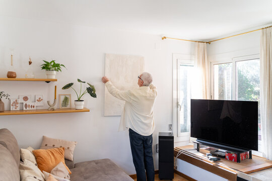 Man Hanging Painting On Wall