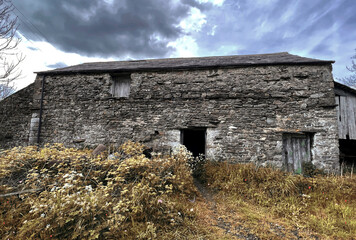 Late autumn, with a weathered stone barn standing under a dark, brooding sky in Stainforth, Settle, UK, 