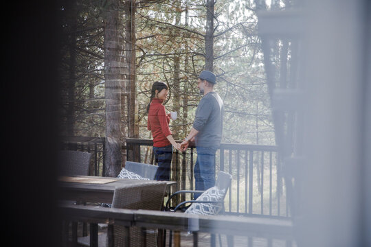 Couple enjoying leisure time seen through glass window in log cabin - Powered by Adobe