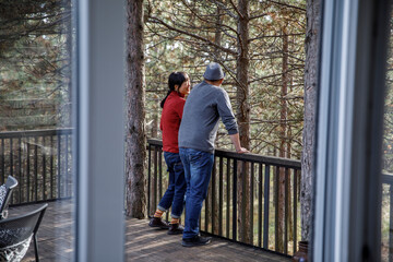 Couple talking in balcony seen through window at log cabin