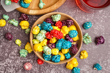 Wooden bowl with sweet colorful popcorn on dark background