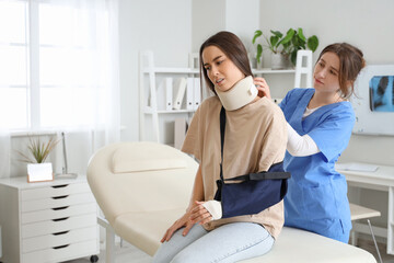 Fototapeta premium Injured young woman with doctor after accident in clinic