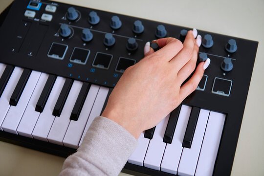 Hands of a woman music producer on a synthesizer.
