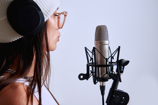 Girl with glasses vocalizing with microphone.
