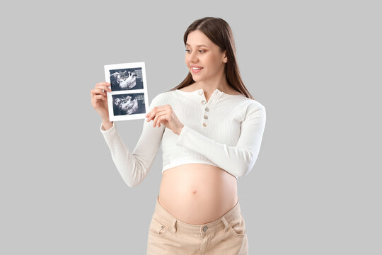 Beautiful pregnant woman with sonogram image on light background