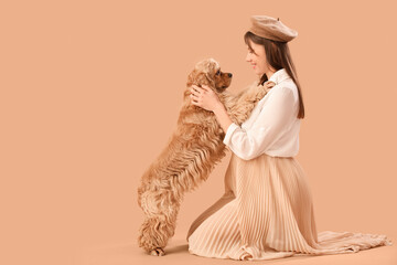 Beautiful pregnant woman with cocker spaniel on beige background