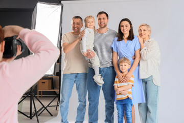 Male photographer taking picture of big family in studio