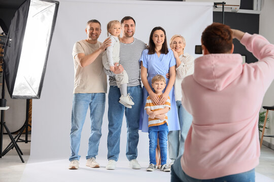 Male photographer taking picture of big family in studio