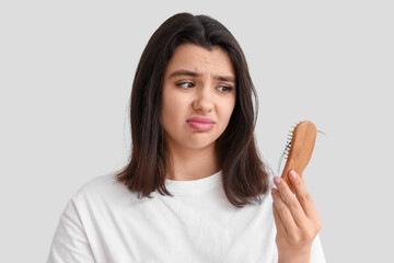 Worried young woman with hair loss problem on white background