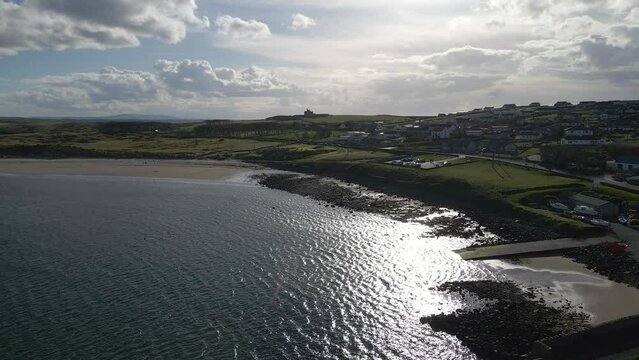 A drone shot of the sun reflecting on the sea with a castle on the horizon.  Mullaghmore Co. Sligo, Ireland