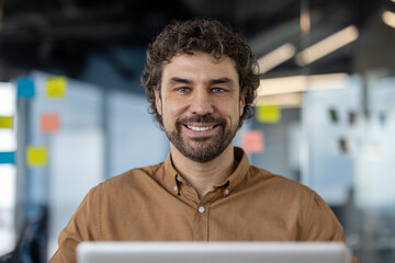 Focused Hispanic man using a computer in a contemporary workspace, embodying professionalism and determination.