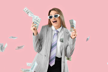 Funny young businesswoman with money on pink background