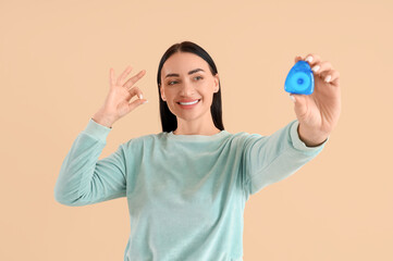 Beautiful young happy woman with dental floss showing OK gesture on beige background