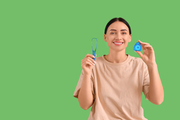 Beautiful young happy woman with dental floss and tongue scraper on green background