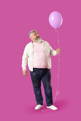 Senior man with lilac balloon on pink background