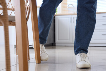 Man tripping over table in kitchen, closeup - obrazy, fototapety, plakaty