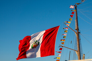 A large flag of Peru flying on the mast of a ship. - obrazy, fototapety, plakaty