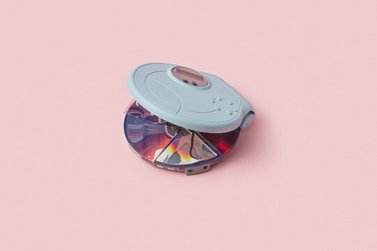 Digital cd player with broken compact disc inside over pink background