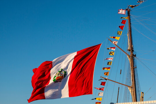 A large flag of Peru flying on the mast of a ship.