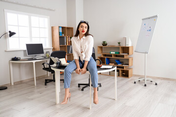 Attractive secretary sitting on table in office