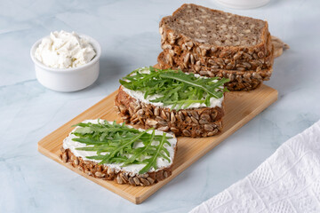 Sandwiches with curd cheese and arugula. Rye bread with seeds