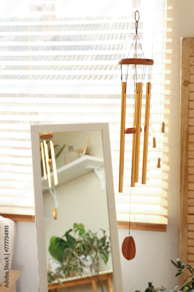 Sticker Golden wind chime hanging in light living room, closeup