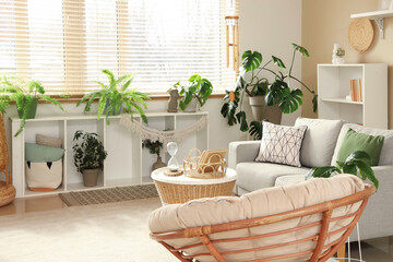 Interior of light living room with wind chime, sofa and plants