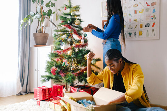 Friends choosing decorations for Christmas tree at home