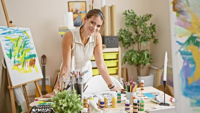 Confident young hispanic woman artist, laughing and enjoying her painting hobby in an art studio, beautiful portrait capturing her creativity