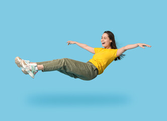 Joyful young woman flying on blue background