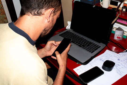 Man at work on laptop smartphone and paper