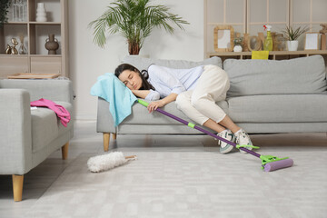 Tired young woman sleeping on sofa after cleaning living room - obrazy, fototapety, plakaty