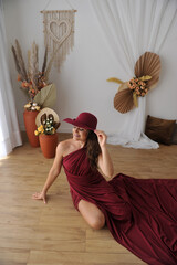 jovem senhora usando chapéu e vestido rubi em sala de luxo boho, fotos dia da mulher 
