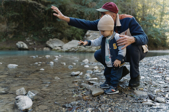 Dad And Son Throw Stones In River