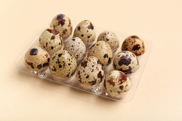 Plastic holder with fresh quail eggs on beige background
