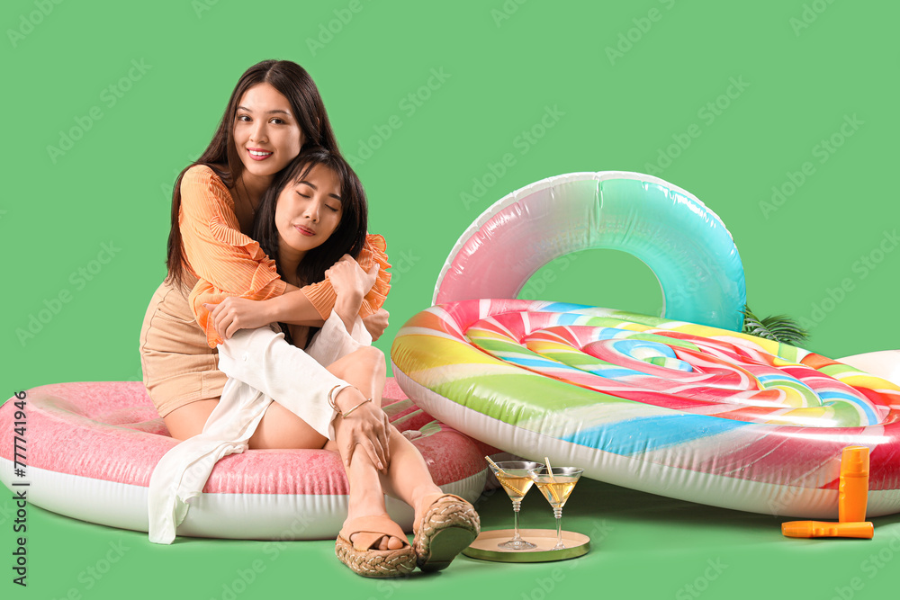 Sticker Female Asian friends hugging on swim ring against green background