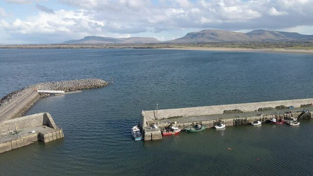 A drone shot showing a pier along the atlantic ocean, with scenic mountains in the background. Mullaghmore Co. Sligo, Ireland.
