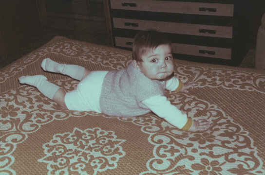 1979. Baby crawls on the bed.