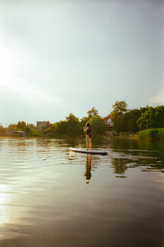 Woman SUP boarding in summer at sunset 